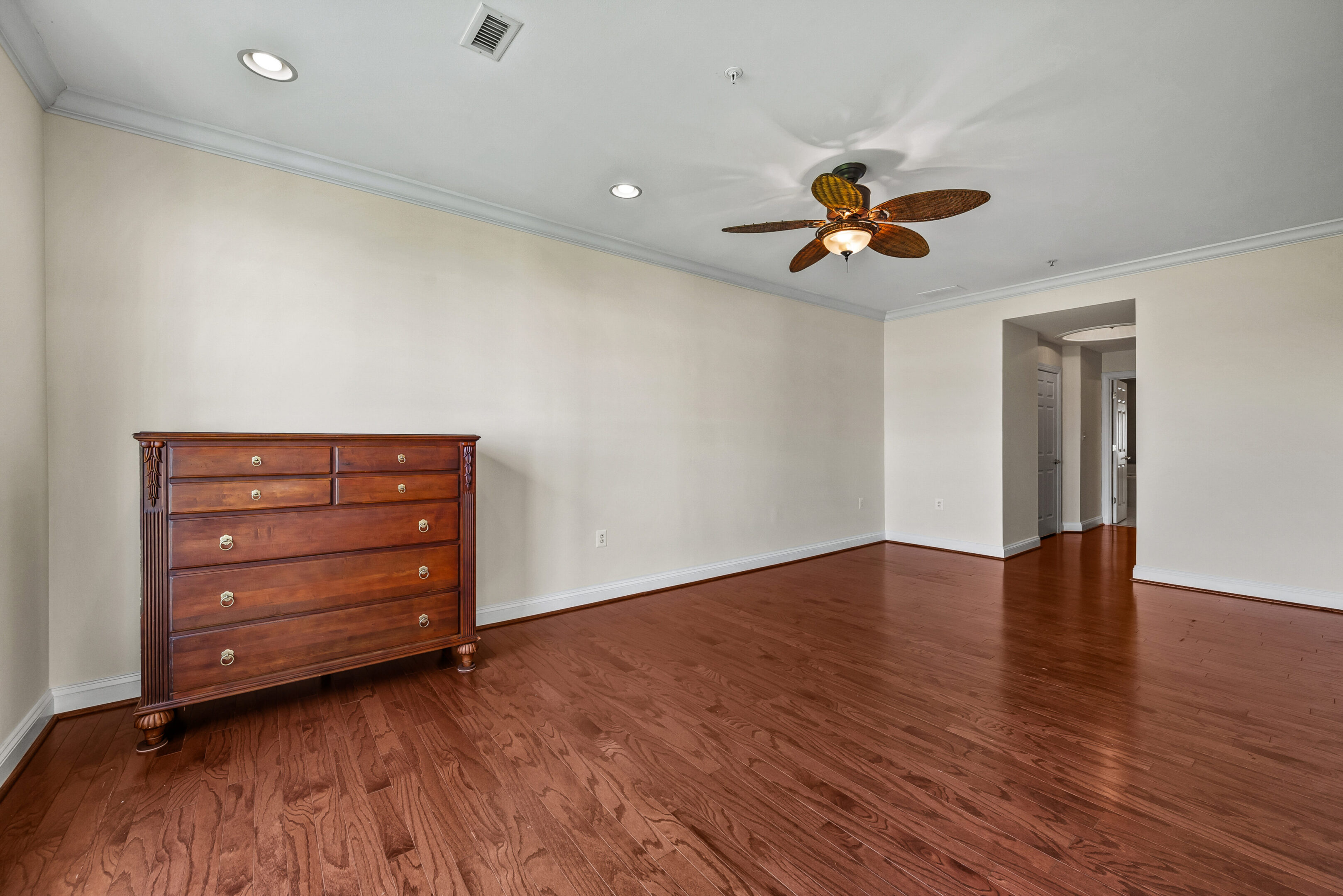 Minimalist room featuring wooden dresser and fan